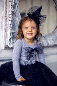 Portrait of a little girl 2 years in the studio in a black mask and a big bow