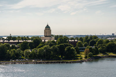 Scenic view of river by buildings against sky