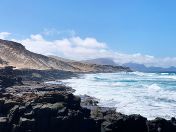 Scenic view of sea and mountains against sky