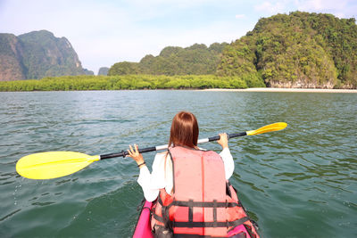 Rear view of woman by river against mountains