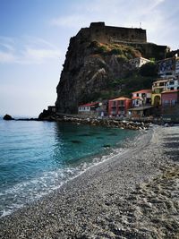 Scenic view of sea by buildings against sky