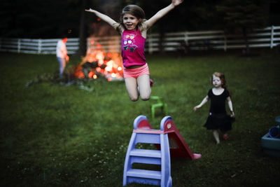 Girl jumping from slide in backyard