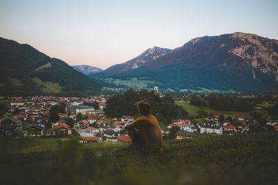 Man sitting on mountain against sky