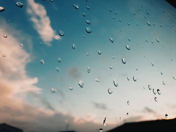 Low angle view of raindrops on glass window