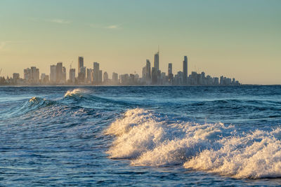 Sea by buildings against sky during sunset