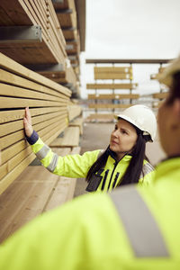 Female worker examining planks with colleague at industry