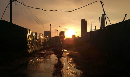 Road by city against sky during sunset