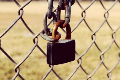 Close-up of padlock attached to chainlink fence