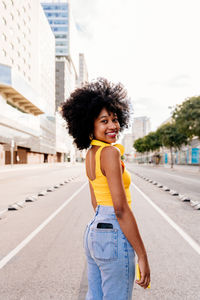 Portrait of young woman standing on road in city