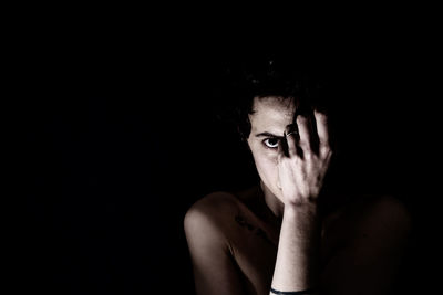 Portrait of young man against black background