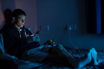 Young man using mobile phone while sitting on bed