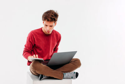 Young man using mobile phone against white background