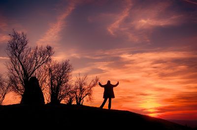 Silhouette of people on landscape at sunset