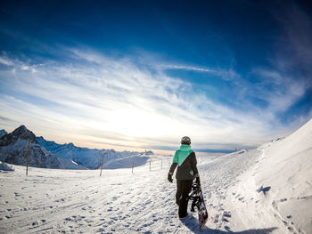 Rear view of person on snowcapped mountain against sky