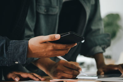 Midsection of man using mobile phone