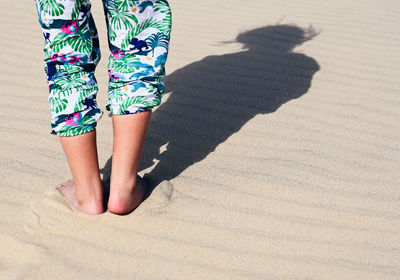 Low section of woman standing on sand at beach