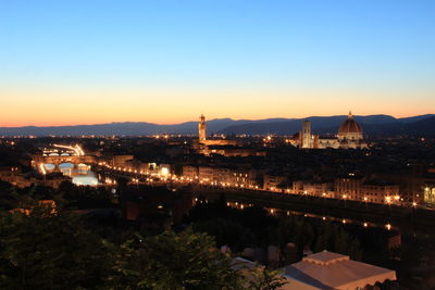 Illuminated city against clear sky at dusk