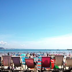 Deck chairs with people enjoying in background at beach