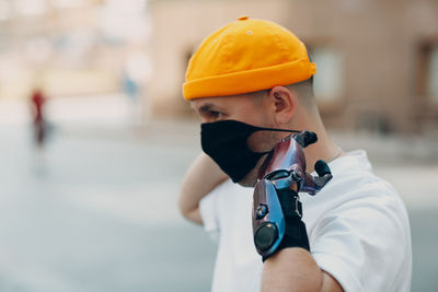 Portrait of man holding camera while standing outdoors