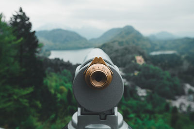 Close-up of coin-operated binoculars against sky and mountains