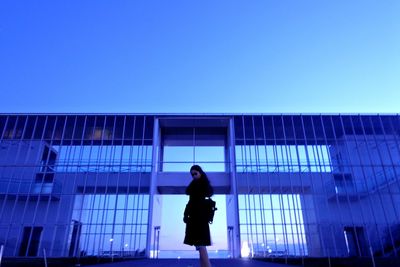 Low angle view of woman standing against modern building