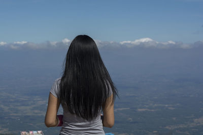 Rear view of woman looking at mountains against sky