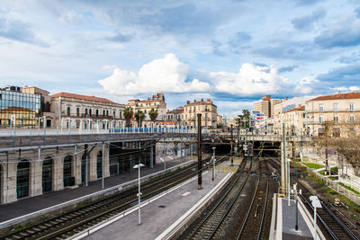 Railroad tracks amidst buildings in city against sky