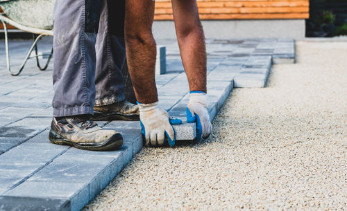 Construction worker arranging paving stones on street