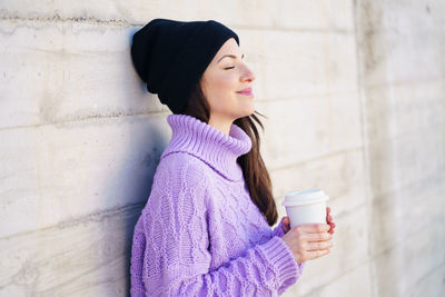 Young woman drinking coffee cup on wall