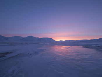 Scenic view of lake against dramatic sky during sunset