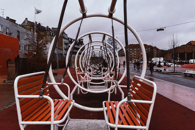 View of empty chairs in park against buildings in city