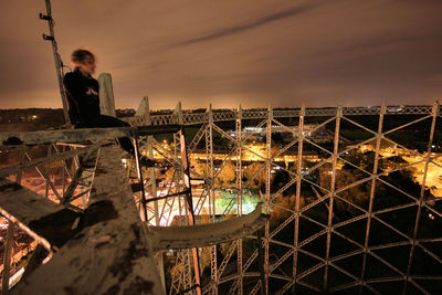 Woman sitting on built structure at night