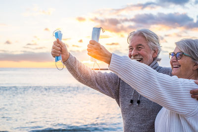 People photographing by sea against sky
