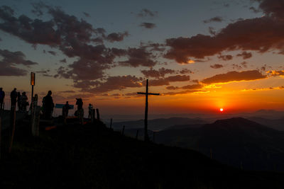 Silhouette people on land against sky during sunset