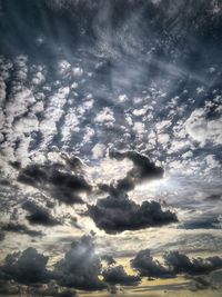 Low angle view of sunlight streaming through clouds