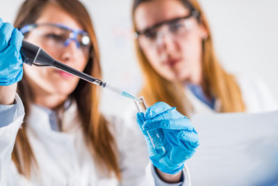 Female scientists examining chemical in laboratory