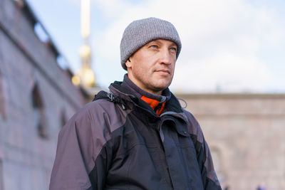 Portrait of an adult man in a gray hat and jacket on the background of the wall person