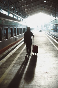 Rear view of man walking on railroad station