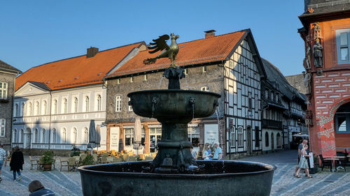 Statue by fountain against buildings in city