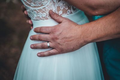 Midsection of couple embracing while standing outdoors