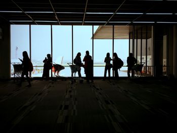 Silhouette people at airport against sky