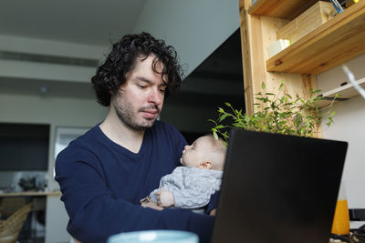 Freelancer working on laptop with baby boy sleeping at home