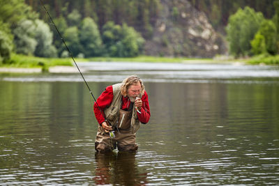 Portrait of man holding umbrella on lake