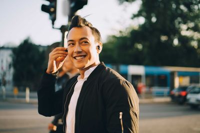 Portrait of smiling man using mobile phone in city