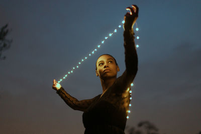 Woman with arms raised standing against sky