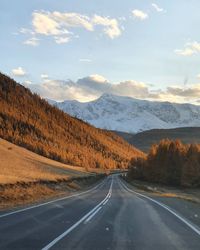 Empty road amidst mountains against sky