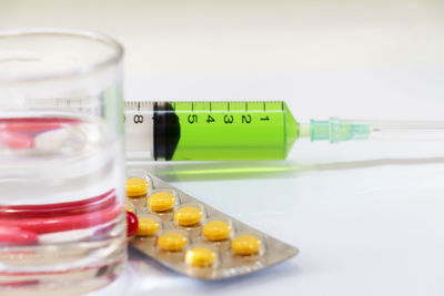 Close-up of pills with syringe on table