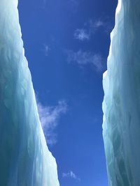 Low angle view of snowcapped mountains against blue sky