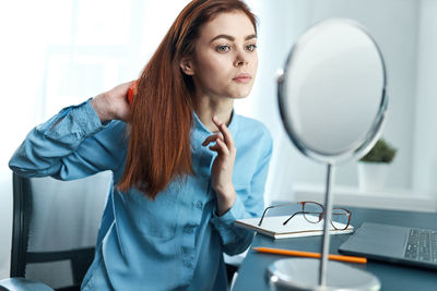 Young woman using mobile phone while sitting on table