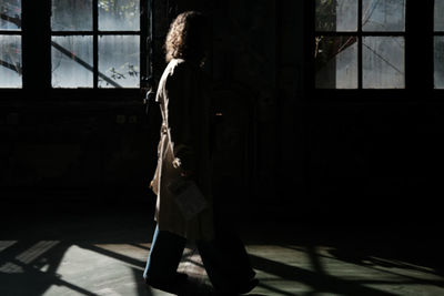 Side view of young woman standing against wall